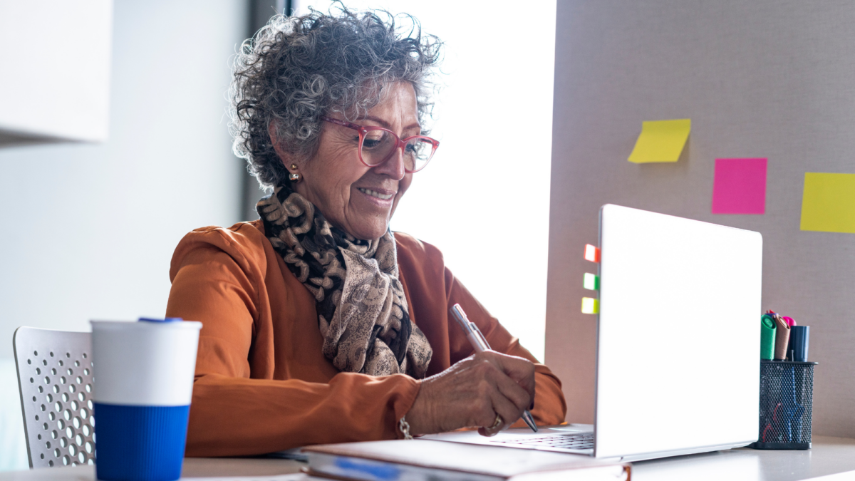 Two older adults in conversation over a laptop in a bright, relaxed environment